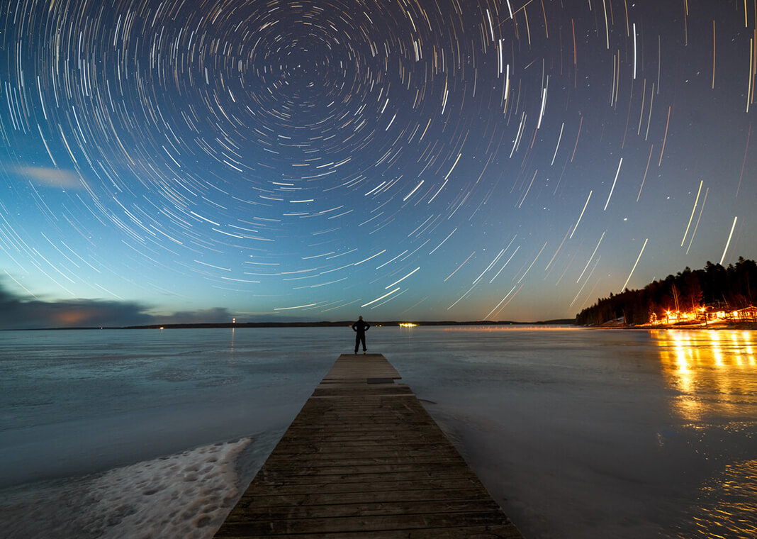 looking at swirls and stars in night sky from pier - © 2017 Samuli Vainionpää/Moment RF/Getty Images