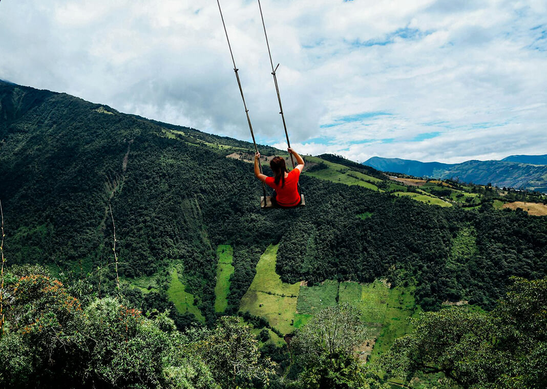 person sitting on large outdoor swing over green field in mountains - photo by Kelly via Pexels